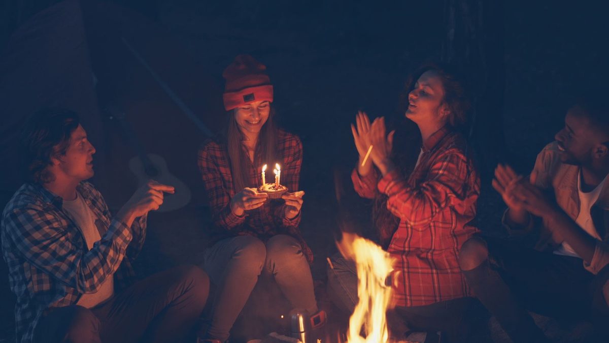 A group of friends gathered around a campfire at night in autumn