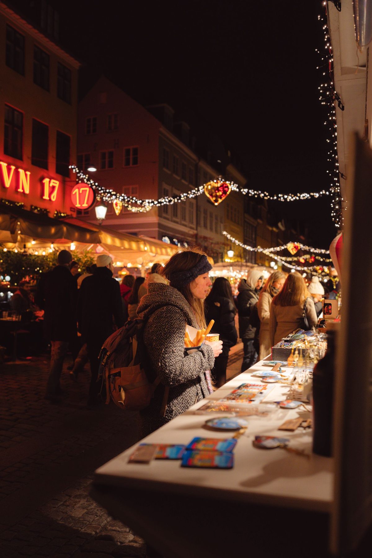 Stalls and shoppers at a European Christmas market lit up at night
