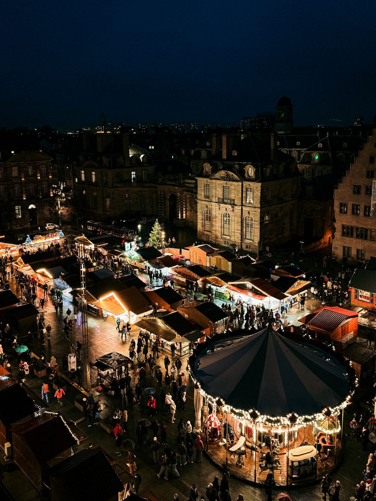 Aerial view of the Strasbourg Christmas market at night with a carousel and lit stalls
